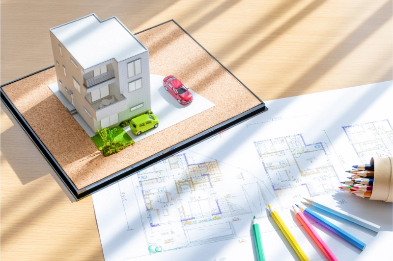 家の模型と設計図の上に色鉛筆